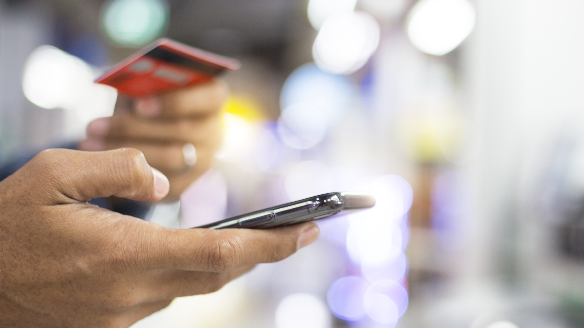 Foto_Whitepaper_Mobile_Banking_AT_1920x1080 Eine Hand, die eine Kreditkarte und ein Handy hält