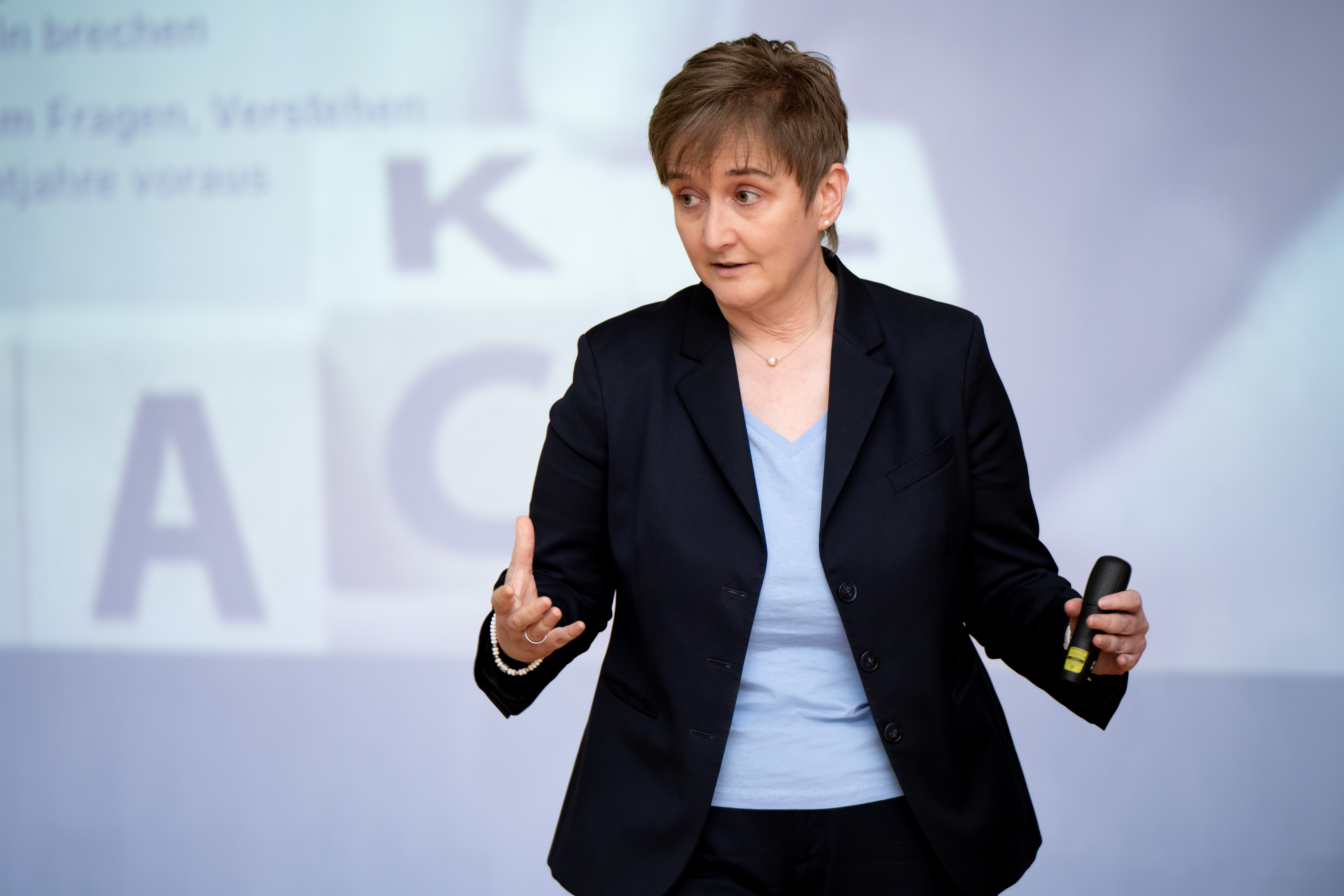 a woman in a suit holding a microphone (Anja Stolz) a woman in a suit holding a microphone (Anja Stolz)