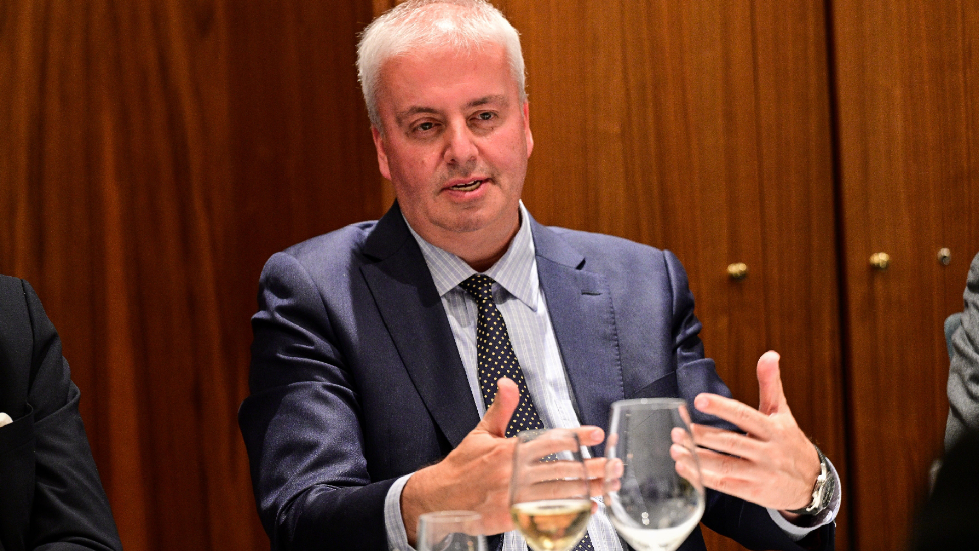 a man in a suit and tie talking to another man a man in a suit and tie talking to another man