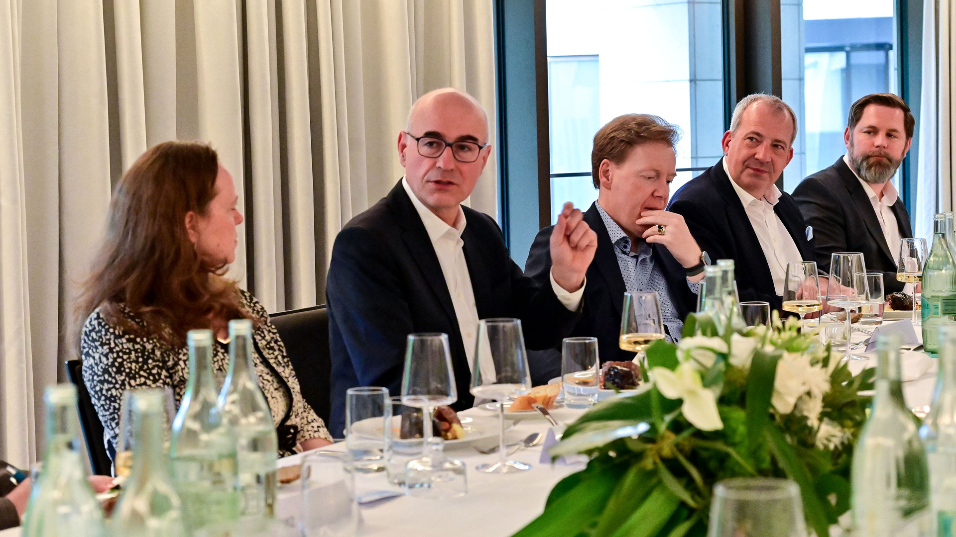 Eine Gruppe von Menschen, die an einem Tisch sitzen Eine Gruppe von Menschen, die an einem Tisch sitzen