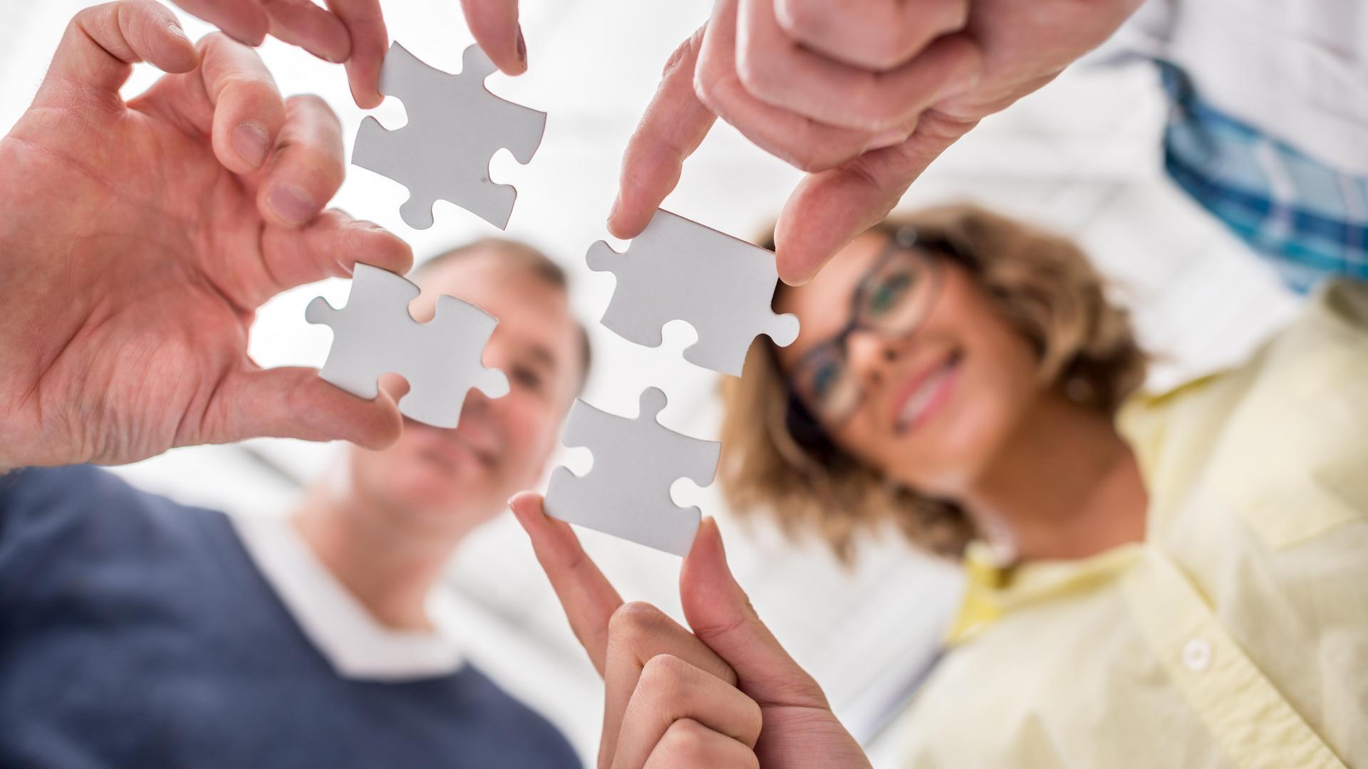 Group of people putting pieces of a puzzle together - problem solving concepts Group of people putting pieces of a puzzle together - problem solving concepts