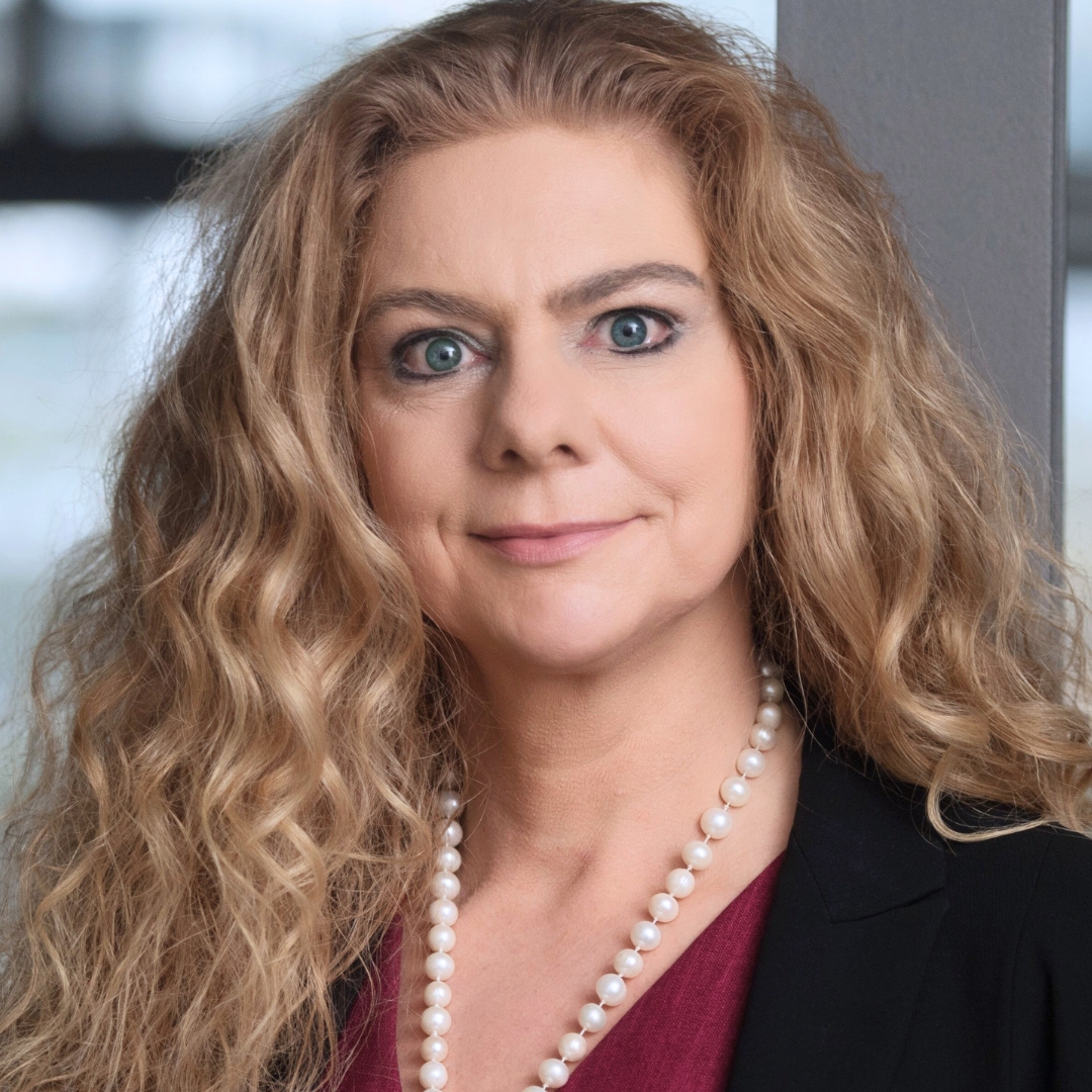 Eine Frau mit langen blonden Haaren, die eine Perlenkette trägt