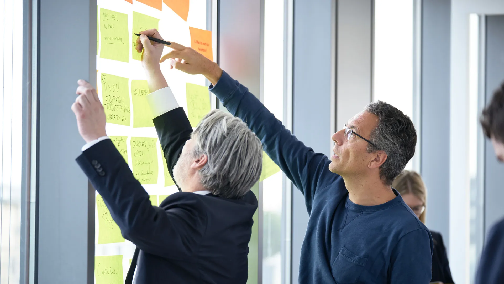 a man writing on a sticky note on a wall