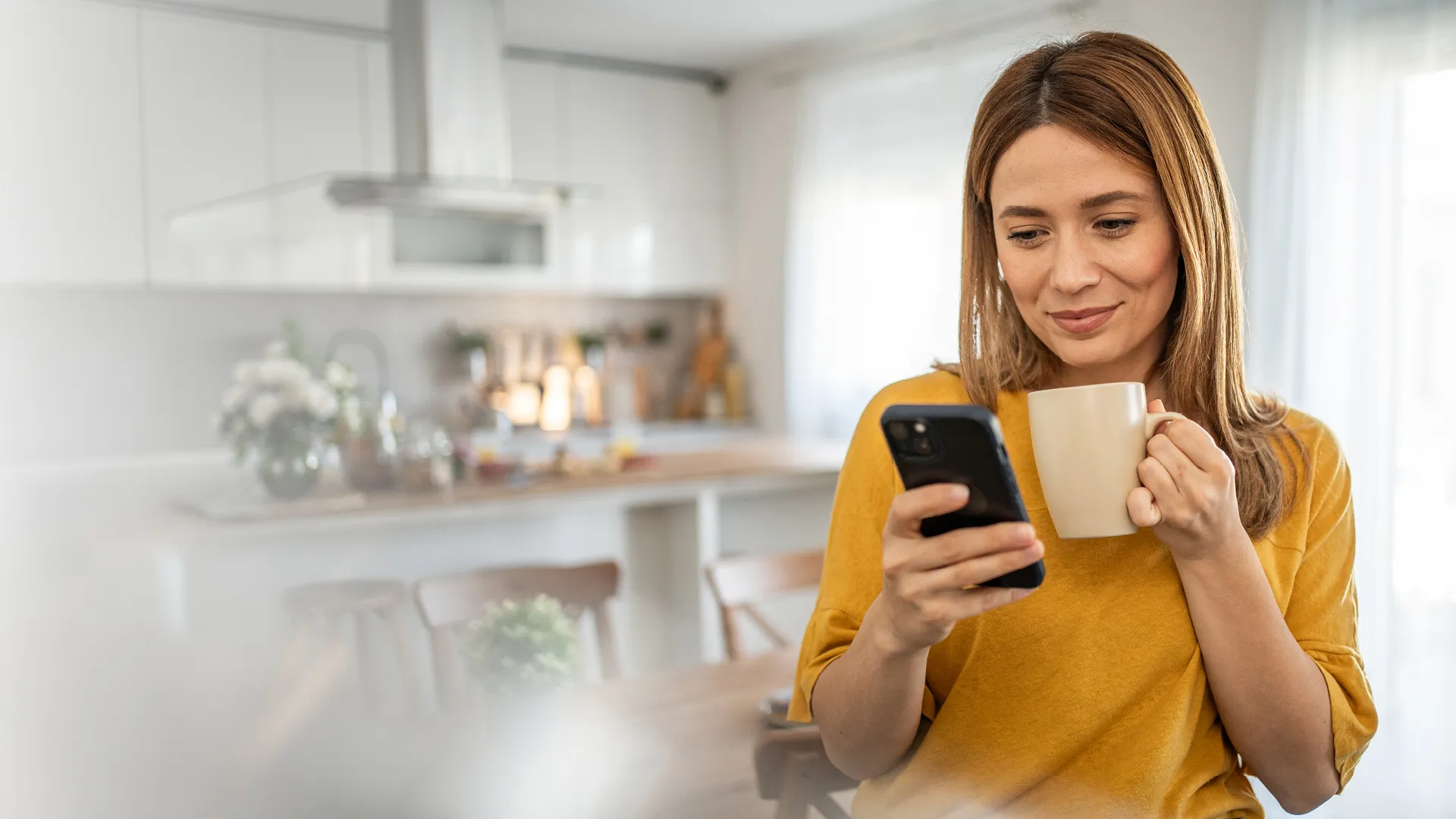 Eine Frau, die eine Tasse hält und auf ihr Handy schaut