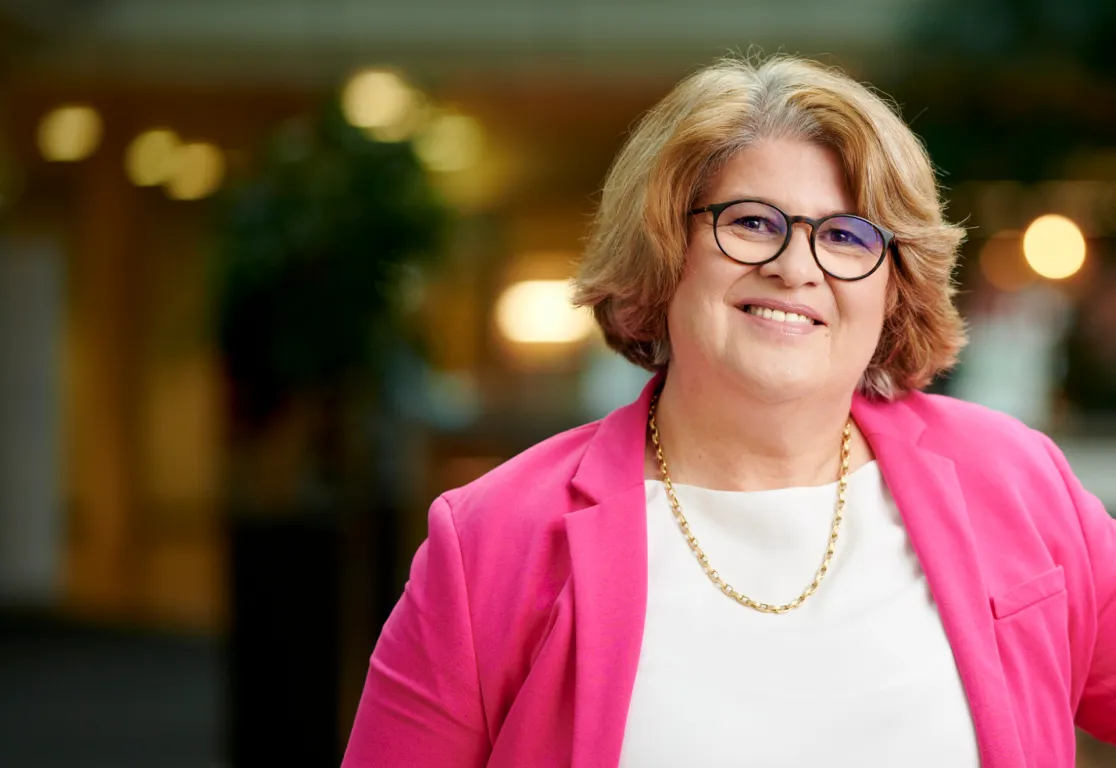 Bild_Interview_Vera_Schneevoigt_1920x1325.jpg Eine Frau mit Brille und rosa Jacke