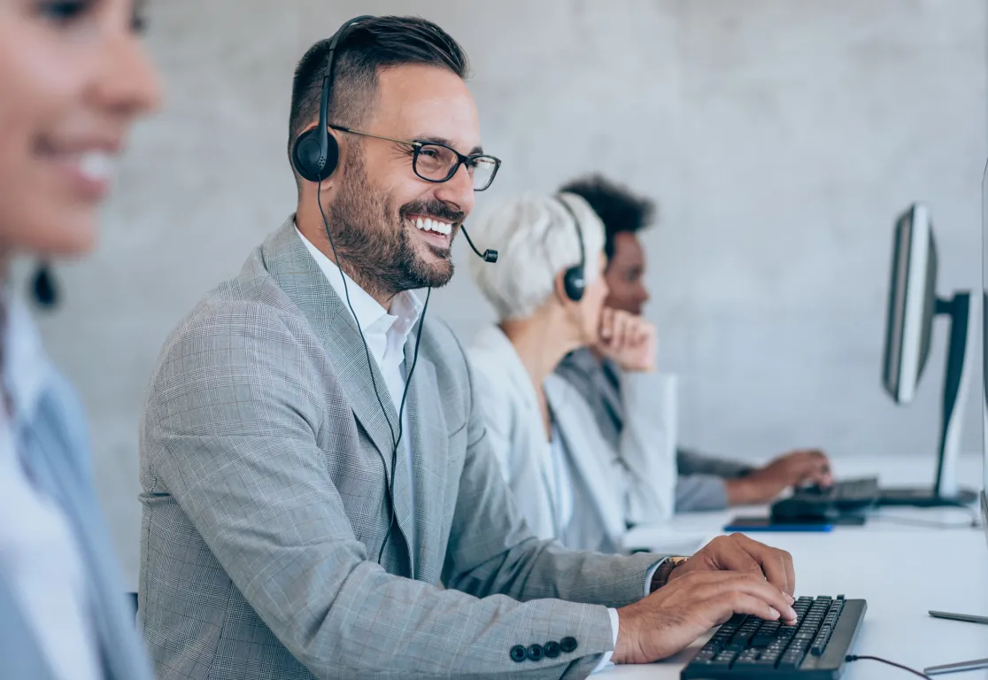 a man wearing headphones and smiling at a computer