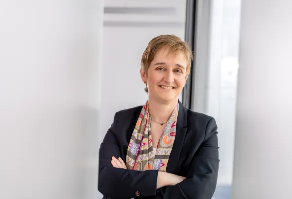 a woman with short hair wearing a suit and scarf