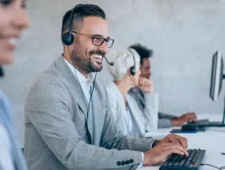 a man wearing headphones and smiling at a computer a man wearing headphones and smiling at a computer