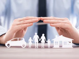 hands covering a family with a house and car
