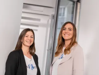 two women standing in front of a glass door