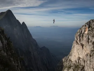 Eine Person balanciert auf einem Seil zu einem Berg.jpg