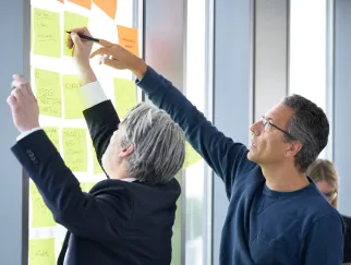 a man writing on a sticky note on a wall