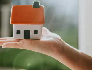 eine Hand, die ein kleines Haus hält