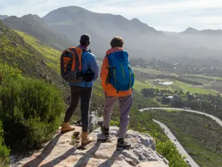 Zwei Menschen, die auf einem Felsen stehen und ein Tal betrachten