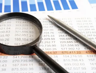 Eine Lupe und ein Stift auf Papier