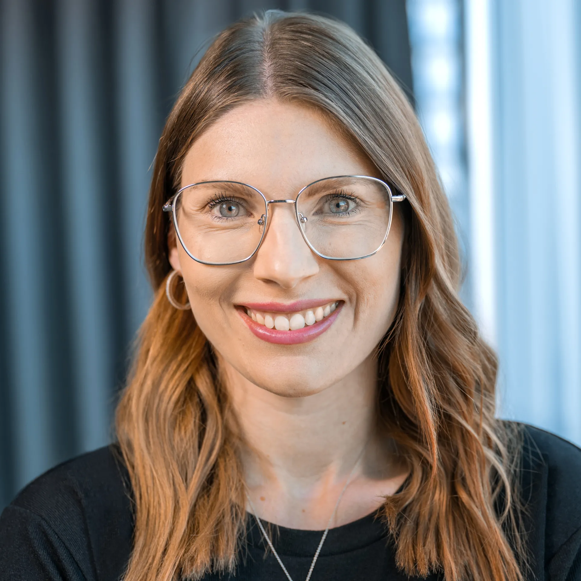 a woman wearing glasses and smiling