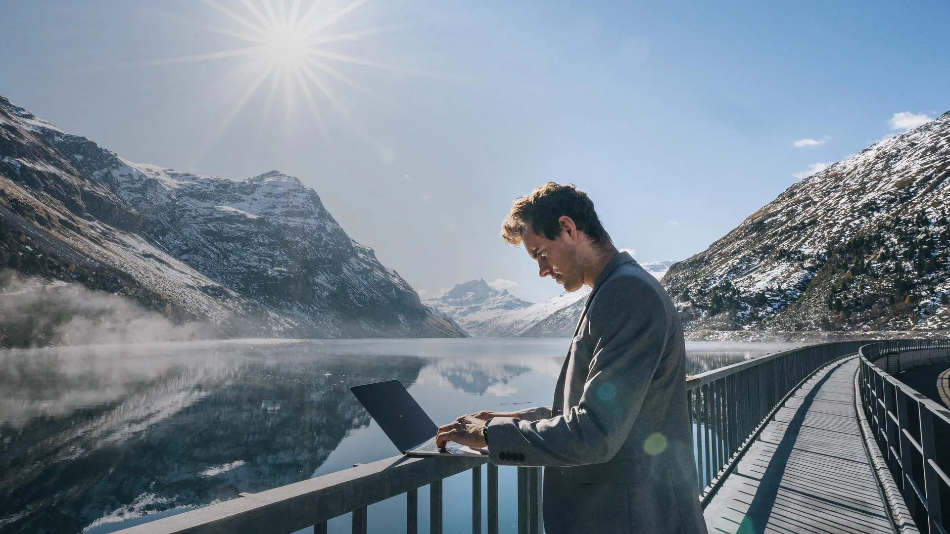 a man standing on a railing with a laptop on his lap