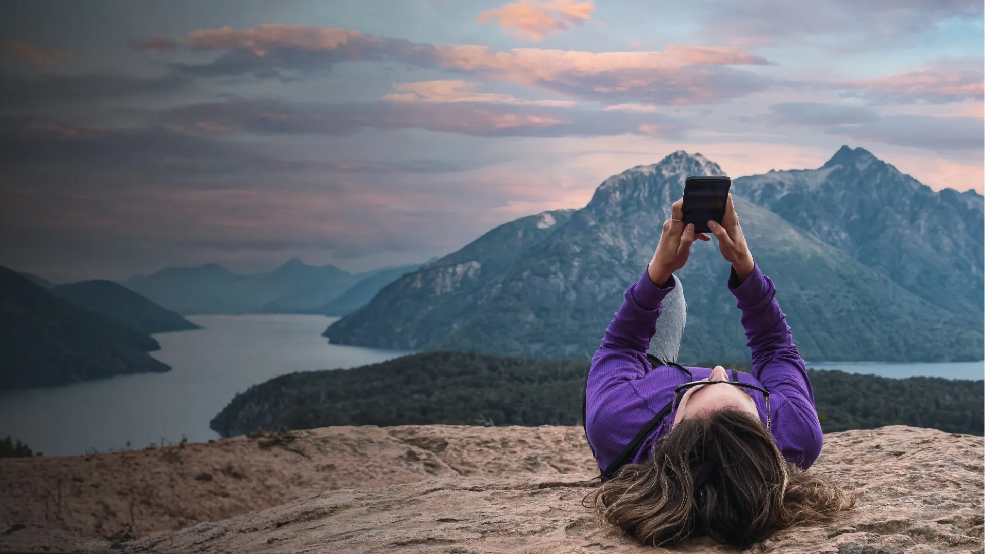 Eine Frau, die auf einem Felsen liegt und auf ihr Handy schaut