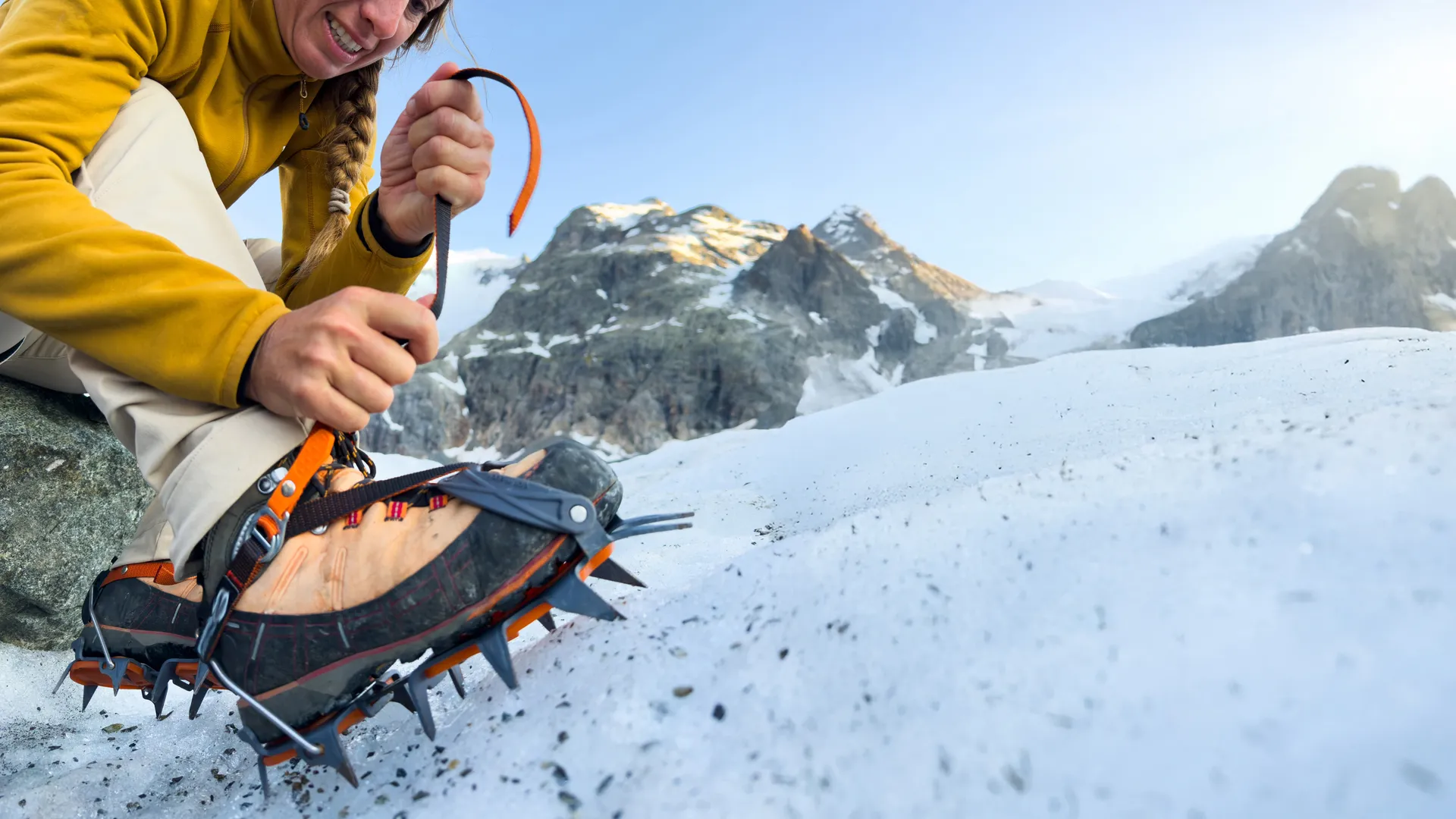 Eine Frau, die auf einem verschneiten Berg einen Schnürsenkel bindet.
