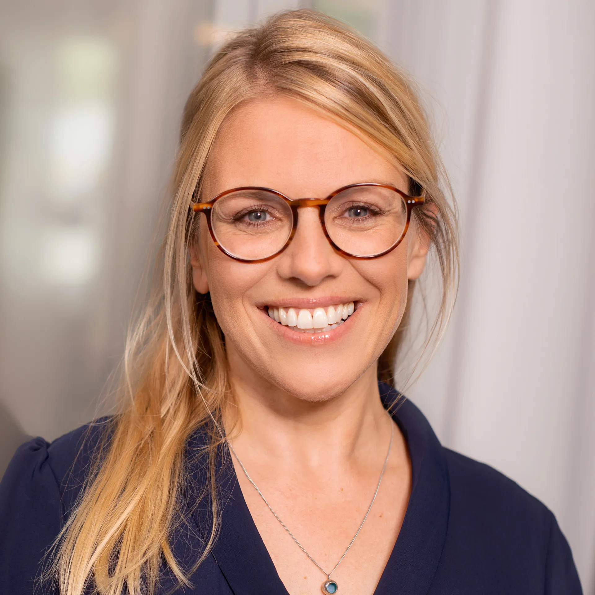 a woman wearing glasses and smiling
