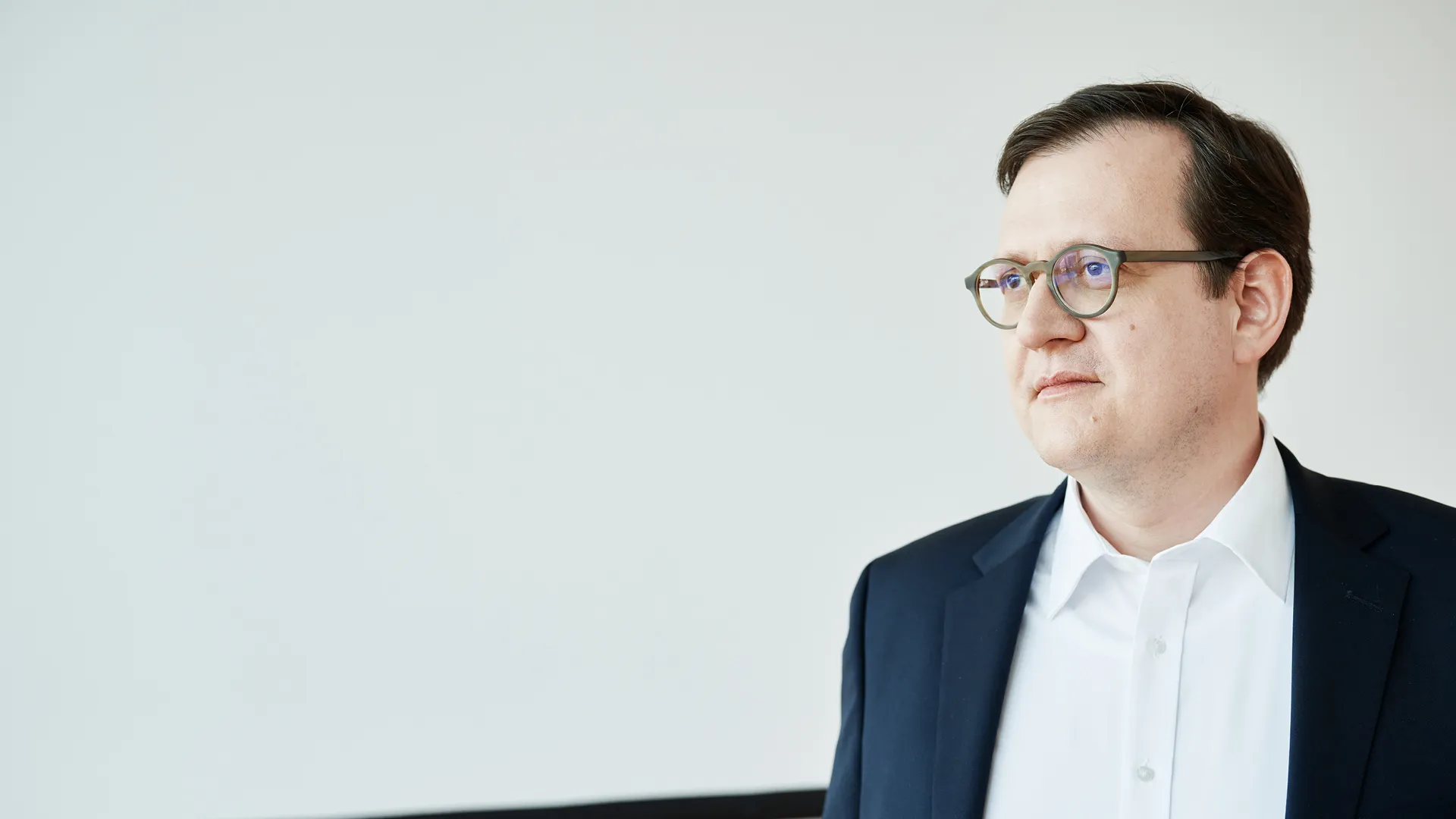 Teaser_Image_Grimm_Simon.jpg Ein Mann in Anzug und Brille