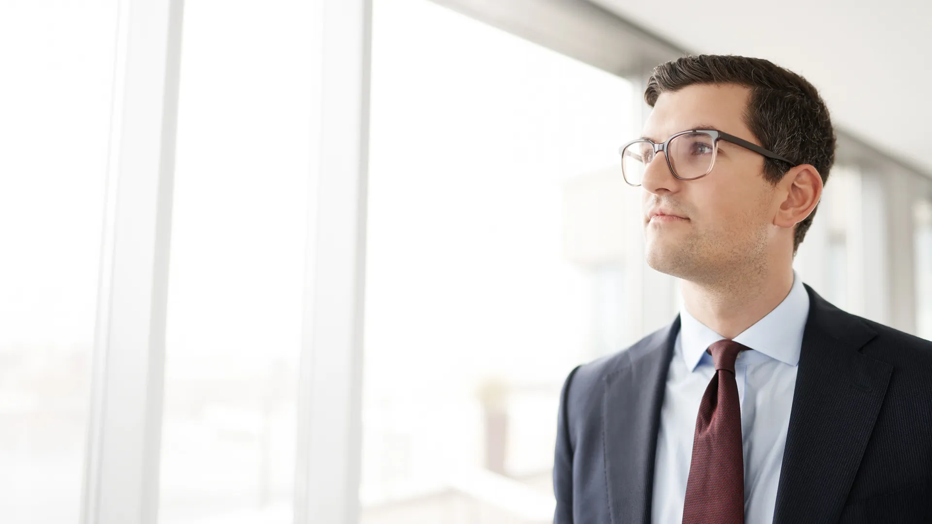 Ein Mann in Anzug und Krawatte, der aus dem Fenster schaut Ein Mann in Anzug und Krawatte, der aus dem Fenster schaut