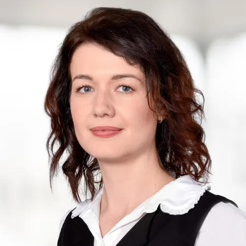 a woman with brown hair wearing a vest and white shirt