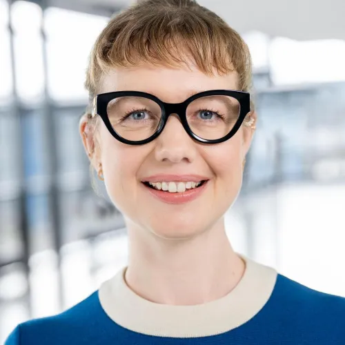 Eine lächelnde Frau mit roten Haaren und einer schwarzen Brille