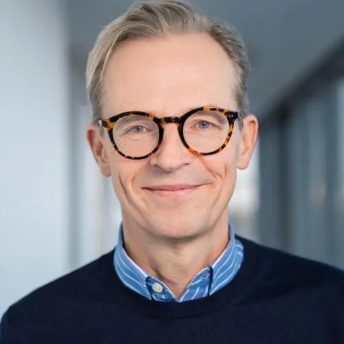 Ein Mann mit Brille und lächelnd